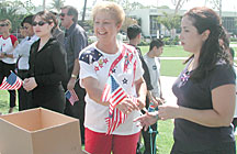 Trudy Foster (center) hands out flags to help students and staff show spirit during the 9/11 service Wednesday.