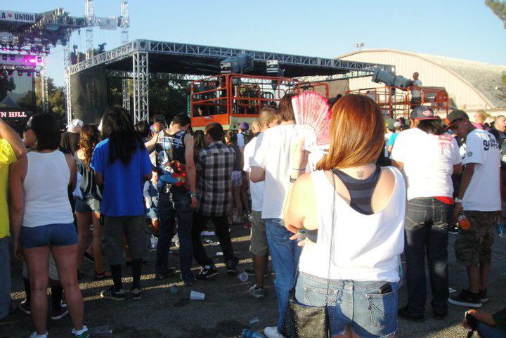 Fans beat the heat at Rock The Bells concert by fanning themselves and going to cool off stations. 