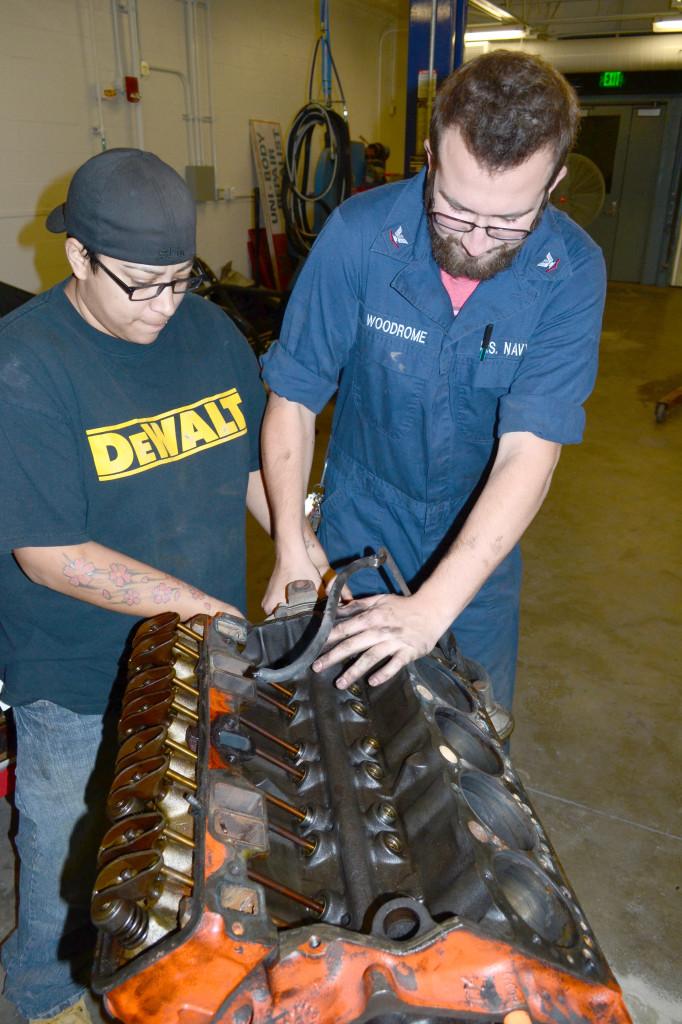 Christina Espinoza, left, automotive business management major, assists Paul Woodrome, political science major, remove a component from the project trucks engine. Four classes in the automotive technology program will share the work on the project truck.