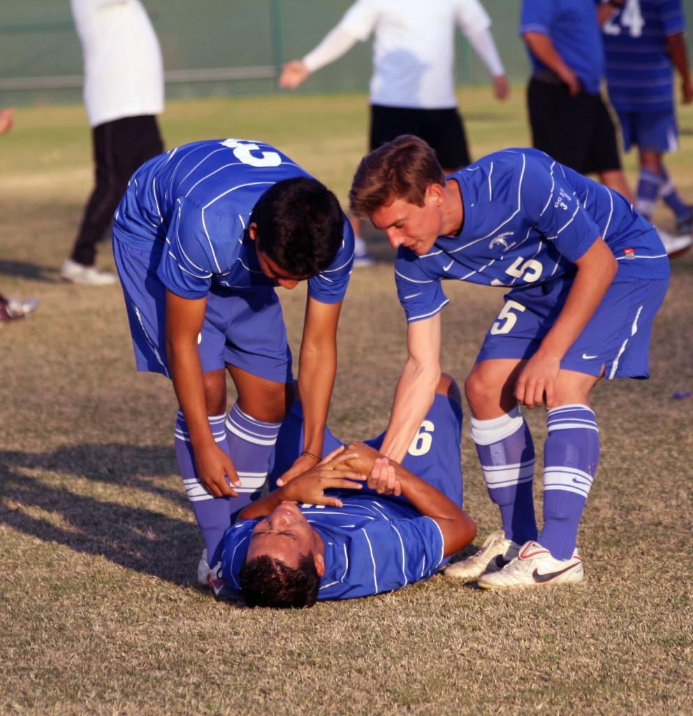 Falcon defender Alex Munoz and midfielder Nicholas Dimatte help up teammate Aaron Macedo after the Cerritos College men's soccer team lost in the second round of the Southern California Regional Playoffs against Golden West College.