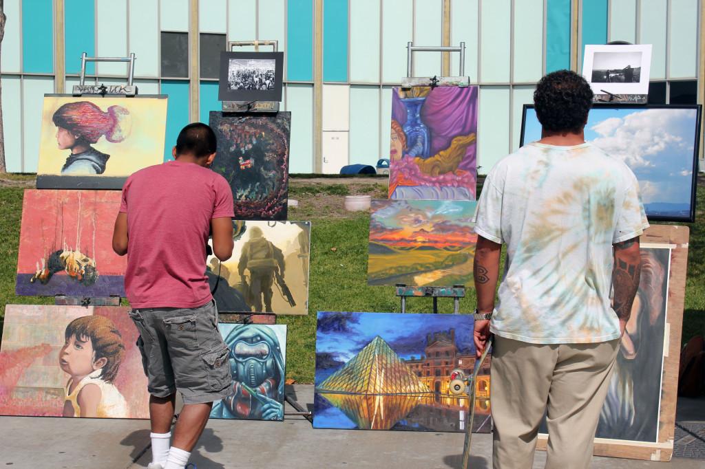Students at Falcon Square looking over at art work made by Artists' Society members for the first Spring art walk. Artists' Society members collaborated with Music Club members for a drum circle at the event.