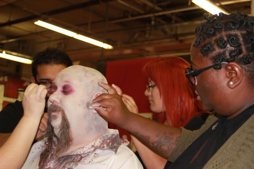Cerritos College students working together to apply a makeup foundation on one of the models who works a as monster at Knotts Halloween Haunt.
