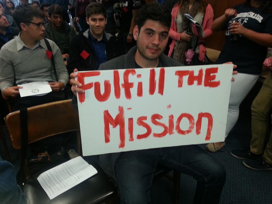 Mauri Nunez, member of The Social Equality Club, holds up a sign that reads Fulfill the Mission in order to support his clubs mission to add 100 sections in the summer session. Photo credit: Alexandra Scoville