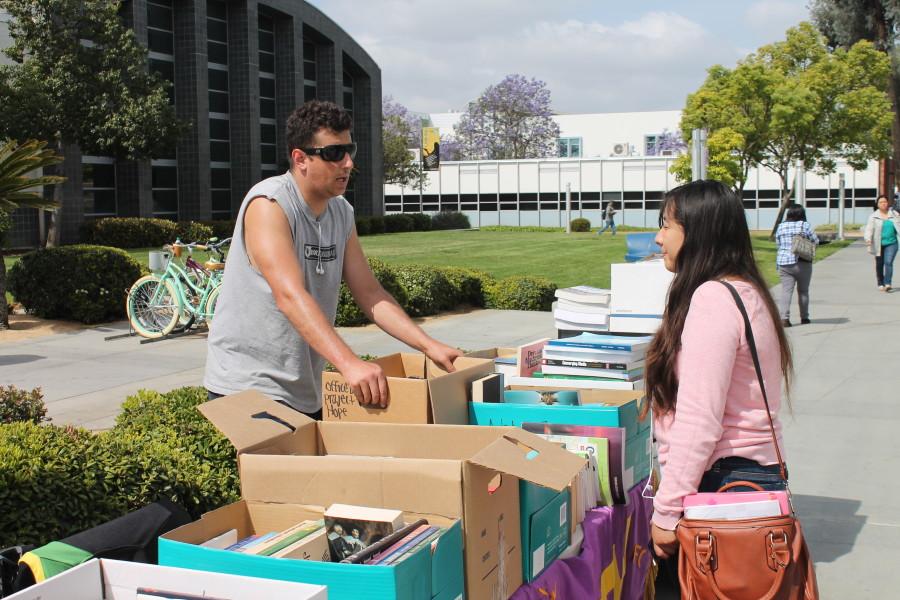Peter Bouris, computer science major, was a Math Club member who explained to passer-by like Yajara Orozco, a child development major, what books were available for sale and that their goal is to help the Su Casa Foundation.