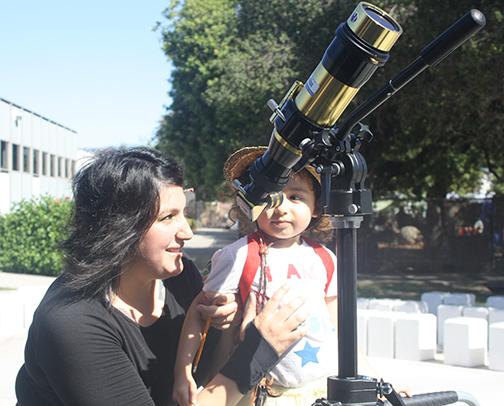Luz Brandsgard, a sociology major, helps her daughter Haylee look into the telescope. Luz likes exposing her daughter to new things. Photo credit: Gustavo Lopez