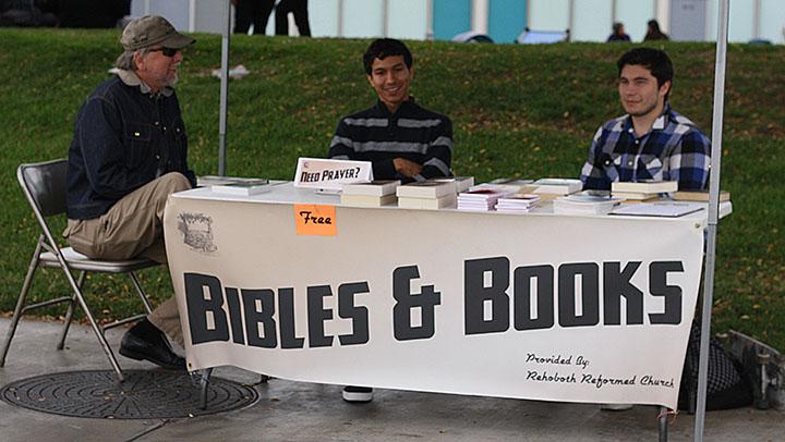 Pastor Mike Voytek, Isaac Chavez, a computer science major and president of the Living Well club, Eric Cabarda, linguistic anthropology major at their booth. They were handing out free bibles and Christian literature to students. Photo credit: Maria Lopez
