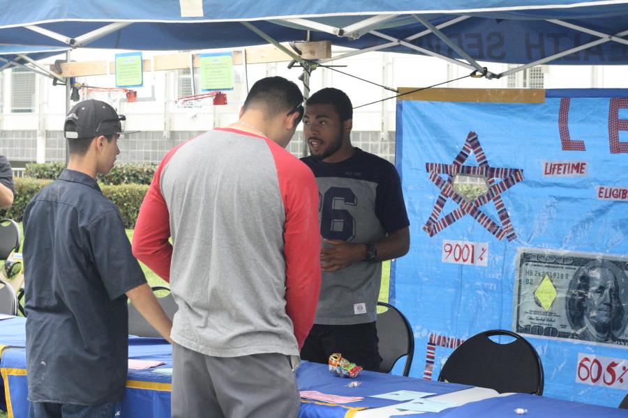 Computer Science major Cornelius Wells helps two students at a game booth during the Financial Aid Awareness Fair. The game booth provided information about FAFSA eligibility. Photo credit: Gustavo Lopez