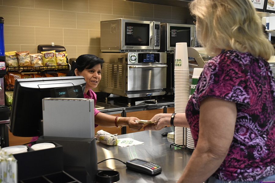 Chhaya Vaidya (left) wife of Subway store owner receiving payment from Subways first customer Pam Chambers (right) educational partnership program and welcome programs assistant II on Friday Aug. 26. Vaidya and her husband will work in the Subway along with 7 other employees. The first sandwich sold was the sub of the day a tuna sandwich. Photo credit: Perla Lara
