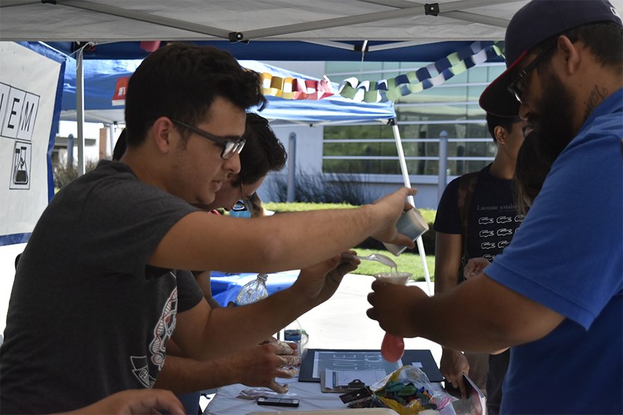 Ahmad Chahine, biochem club member (left) helping Avid Diaz (right) make a stress ball out of cornstarch water and a balloon at the fifth STEM open house at Cerritos College on Friday Sept. 30. The clubs at the open house wanted to show the fun side to science by playing games, and making things like silly putty, stress balls and ice-cream. Photo credit: Perla Lara