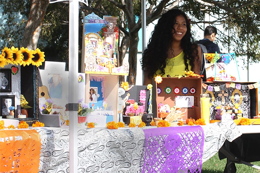 Psychology major and MEChA member Stephanie 
Nunez stands behind an altar for DÍa de los Muertes to memorialize loved ones who have passed. The club also had traditional snacks and face painting available for students to try. Photo credit: Bianca Martinez