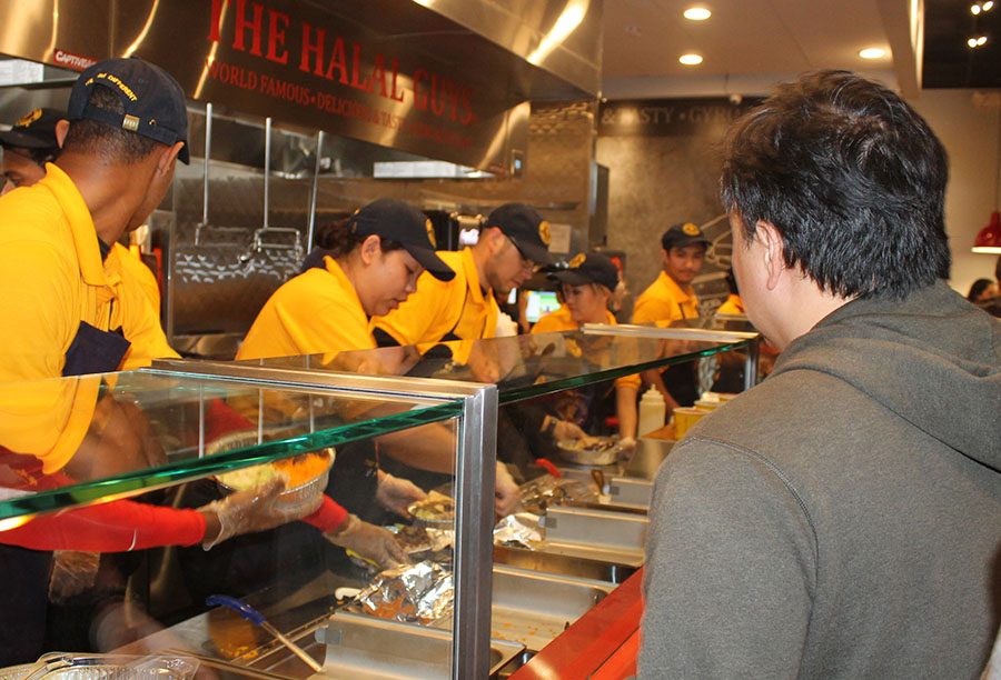 Employees of The Halal Guys line the buffet line to serve customers at the soft opening. The restaurant is located at the Los Cerritos Promenade. 
