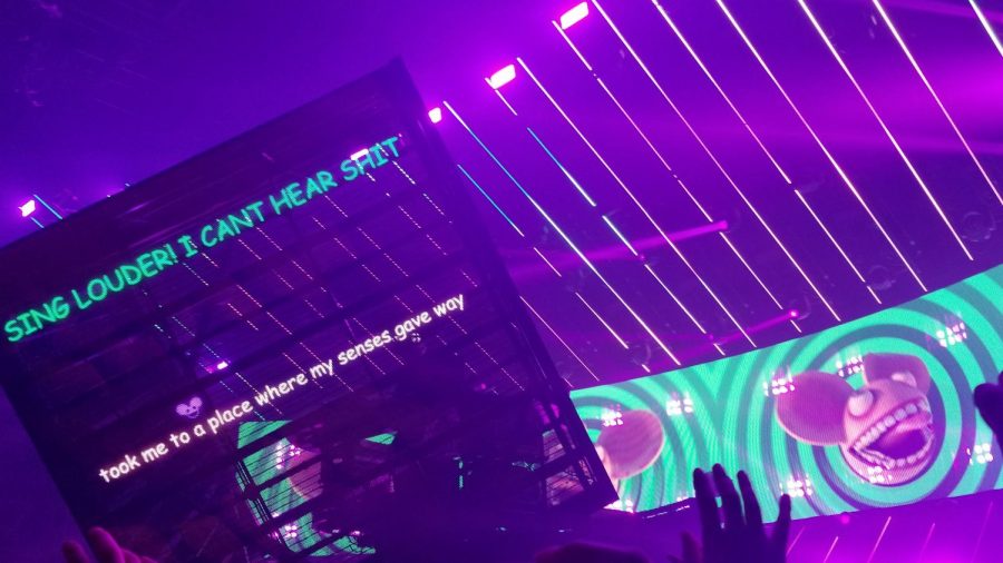 As Deadmau5 performs, he types messages onto his cube along with crazy imagery on the background. Fans are mesmerized by the music along with the lights.