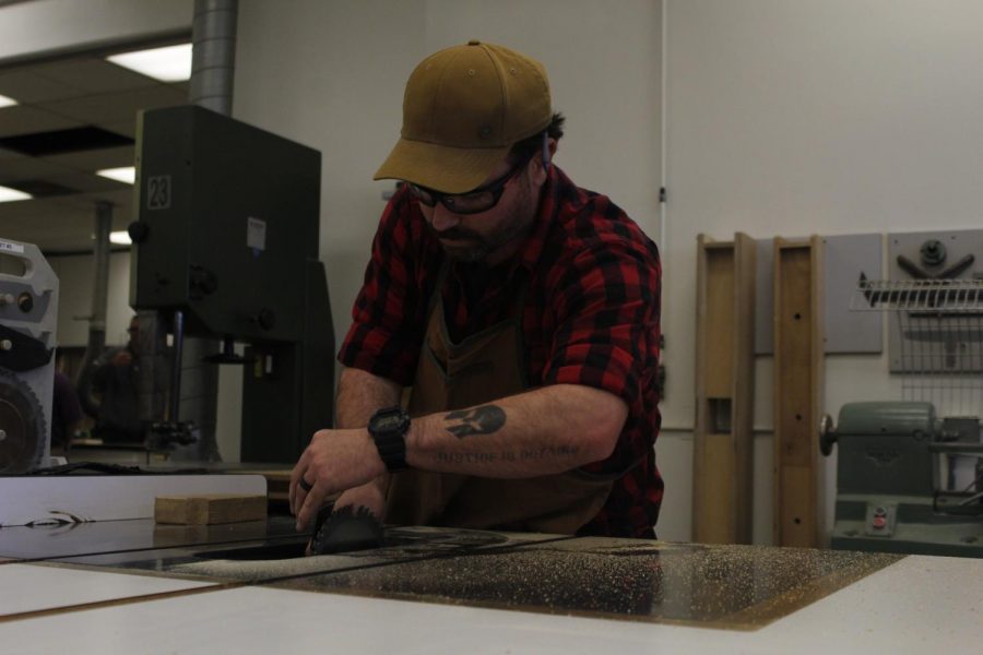 Travis Smith, a woodworking major at Cerritos College, cuts planks for a dresser.
