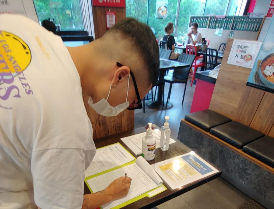 Dining guest fills out mandatory customer log with their contact information before entering a local restaurant. Restaurants and bars are required to keep a log of all their visitors for contact tracing purposes. Photo credit: Mirella Vargas