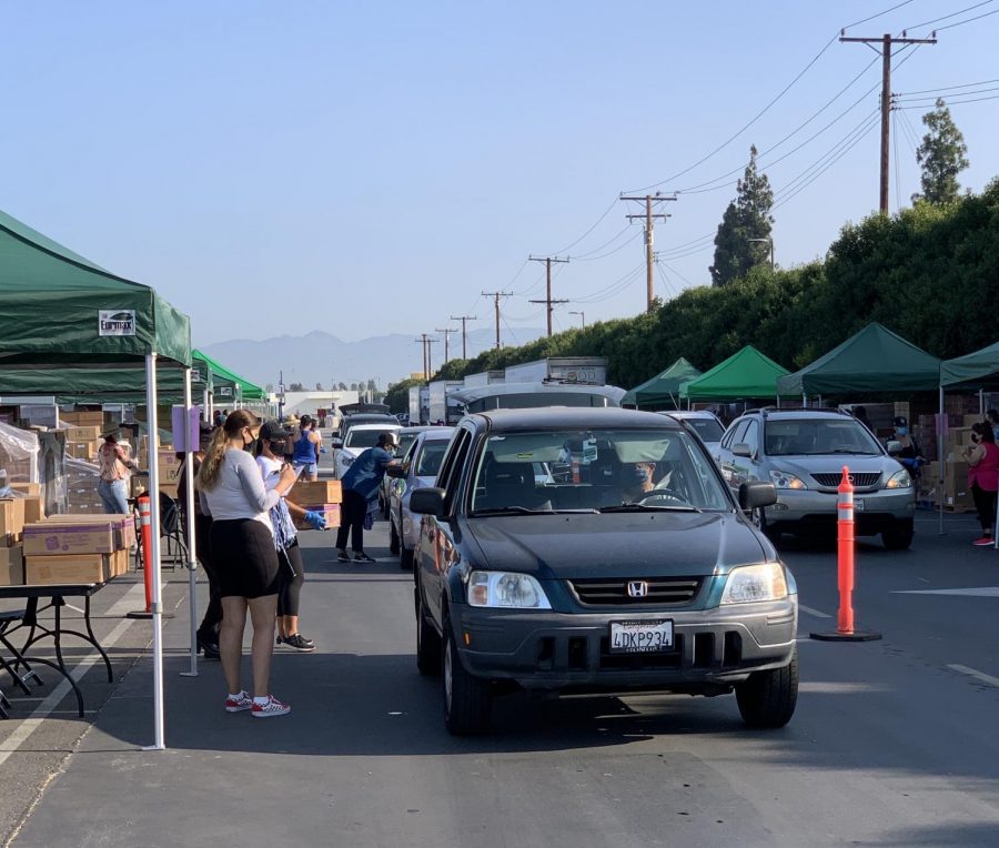 Drivers wait in line as volunteers fill their cars with food. For the safety of everyone drivers are not allowed to exit their vehicles. Photo credit: Eileen Osuna