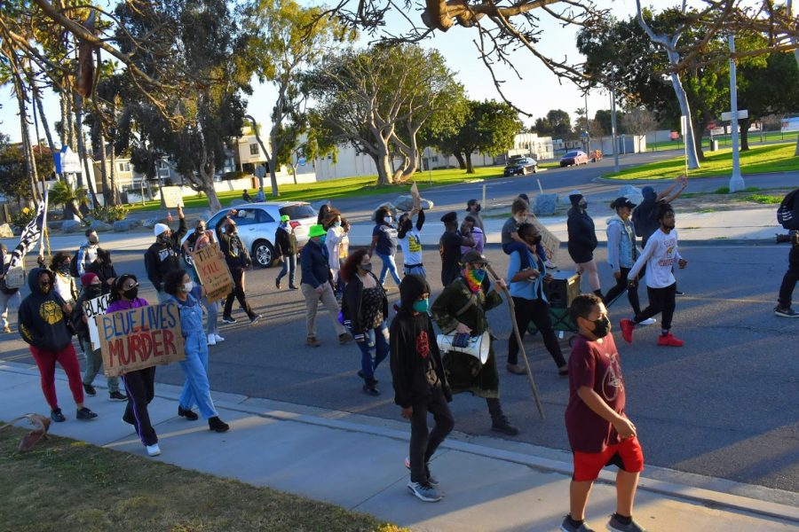 Dozens march during a Black History Month celebration to advocate for social justice reform and the defunding of law enforcement. They marched through Marina Park in Long Beach on Feb. 20, 2021.