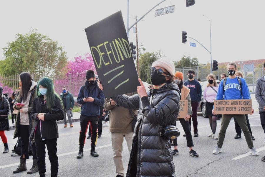 BLM supporter Sara McLean supports the initiative to defund the LAPD during a protest on March 8, 2021. She raises her hand-painted sign in solidarity with the movement.  