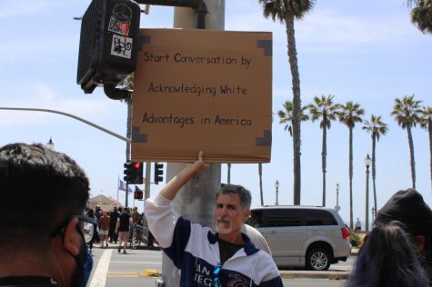 Huntington Beach resident Tom McNamara protested the KKK organized event in his community. He held a sign pushing for a conversation about race in America, on April 11, 2021.