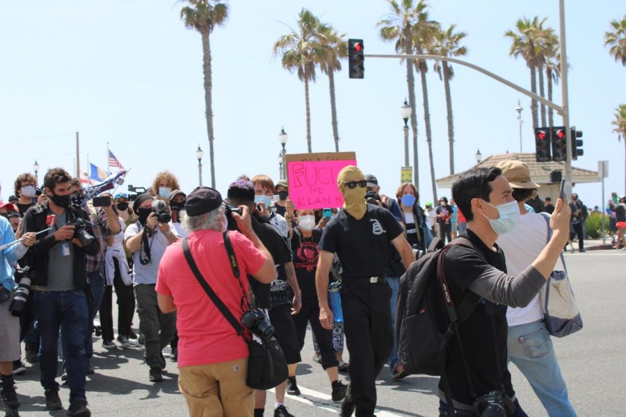 A right-wing agitator is pursued by a crowd at the Huntington Beach Pier. The man was chased until he was escorted by police into a substation on April 11, 2021. Photo credit: Lola Ajetunmobi