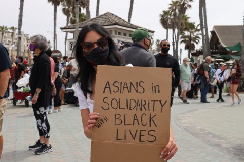 Former Huntington Beach resident Ann Tran says she experienced racism when she lived there. She holds a sign expressing anti-racist solidarity on April 11, 2021.