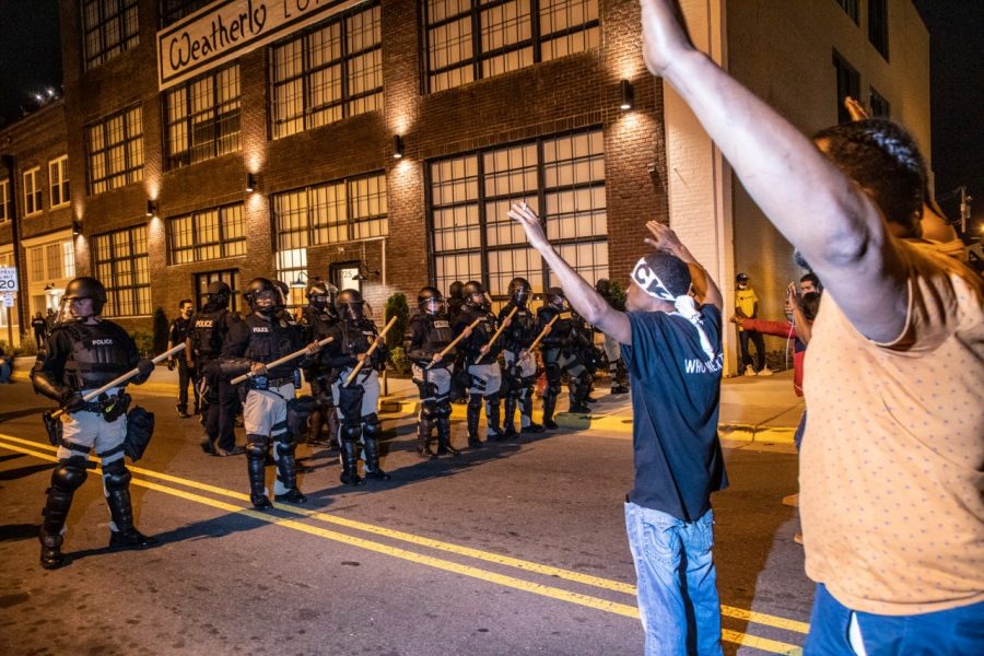 A demonstrator protesting the police killing of Andrew Brown Jr. raise their hands in front of a police line Tuesday, April 27, 2021, in downtown Elizabeth City. At least six protesters were arrested when police in riot gear marched toward roughly a dozen protesters two hours past curfew. Protesters were peaceful but refused to clear the streets.