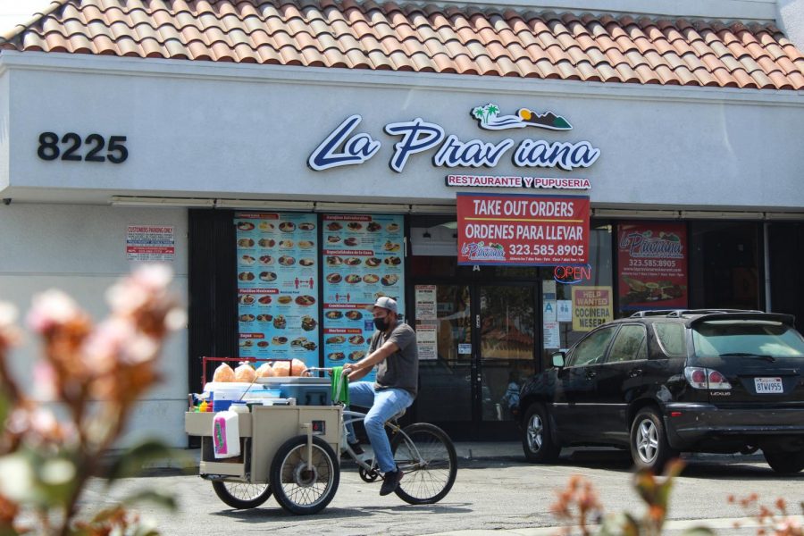 A street vendor rides in front of popular Salvadoran restaurant, La Praviana. The South Gate restaurant, 8223 Long Beach Blvd, is known for 12 different pupusa recipes. 