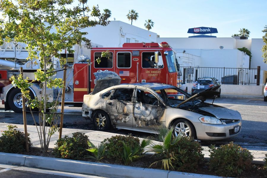 A Chevy sedan catches fire across the street from Norwalk Town Square on April 29, 2021. LA County Fire Station 20 arrives quickly to extinguish the flames.