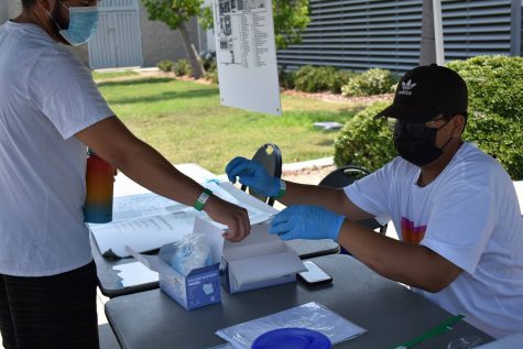 Meximos Garcia gives a wristband to a student at the library health screening kiosk on Monday, Aug. 16, 2021. The wristband shows that the student is safe to enter campus, and has no COVID-19 symptoms.