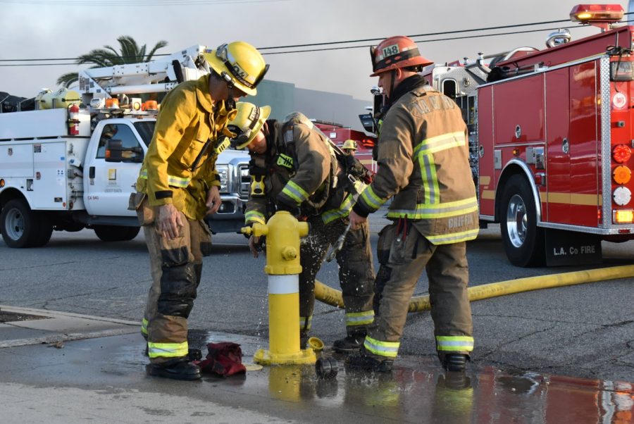 Firefighters work to hook up their hose to the fire hydrant. They hurry to extinguish  the fire in Bellflower on Nov. 9, 2021. 