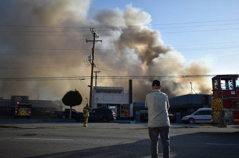 Extra Space Storage facility bellows out black smoke from a massive fire in the facility. Bystanders watch as firefighters start attacking the flames on Nov. 9, 2021. 
