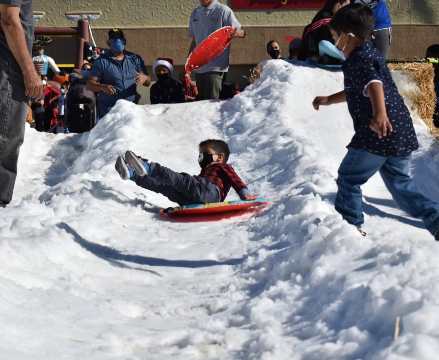Danny Mondragon watches as his son slides down a mound of snow. The Cerritos College alumnus brought his family to the Norwalk town square for their Christmas festival on Dec. 11, 2021.