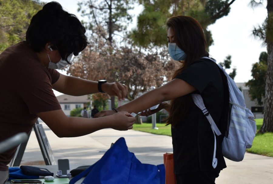 Students receive their wristbands before entering Cerritos College campus. Their wristband confirms they have no symptoms of COVID-19. 