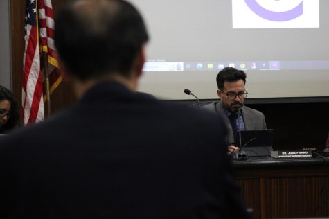 President/Superintendent and a Board of Trustee member, Dr. Jose Fierro, intently looks at his tablet in the background as he looks at the next agenda items during March 22s board meeting.
