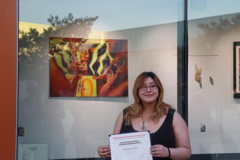 Clarissa Soto behind her portrait, holding the 2nd place award in paintings at Cerritos College on April 27 