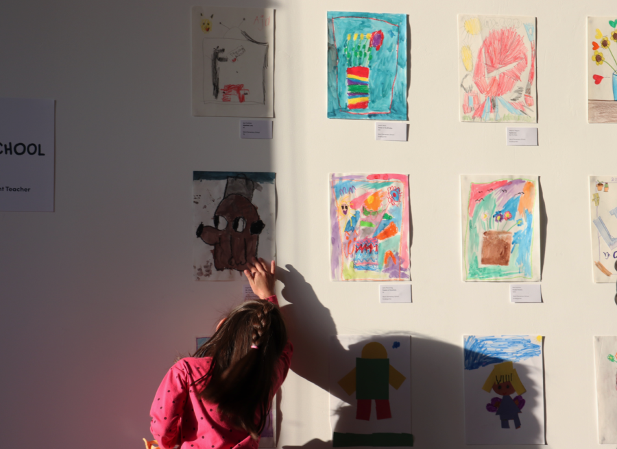 Student twirling and observing her and her classmates artwork on the Stay Gallery walls on May 2. 