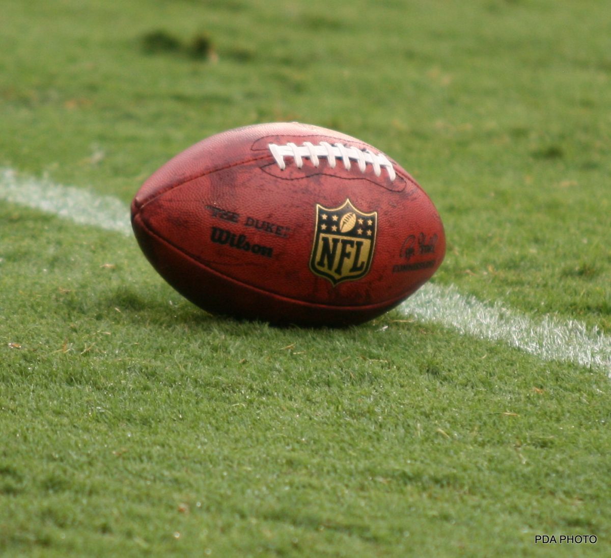 Picture of an NFL football on a football field. Photo credit: Parker Anderson