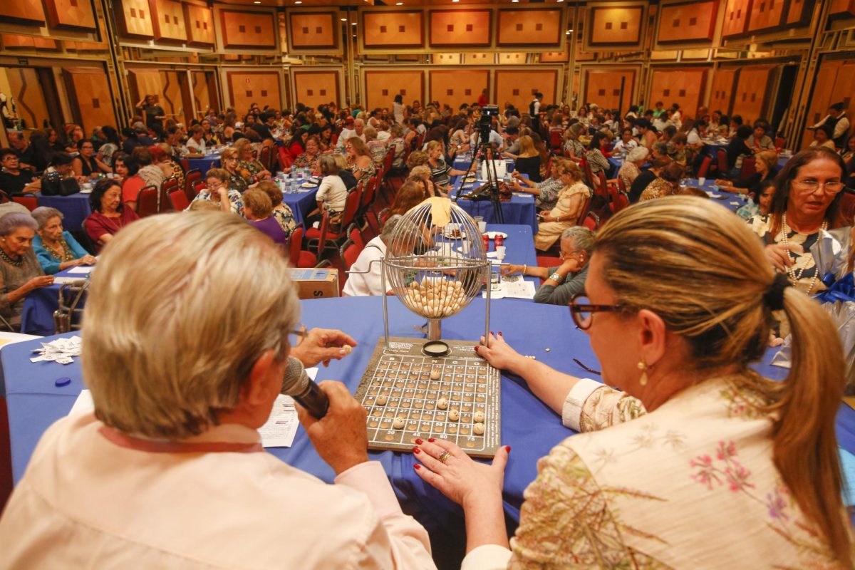 Two women calling out numbers for hundreds of people during a bingo event. 