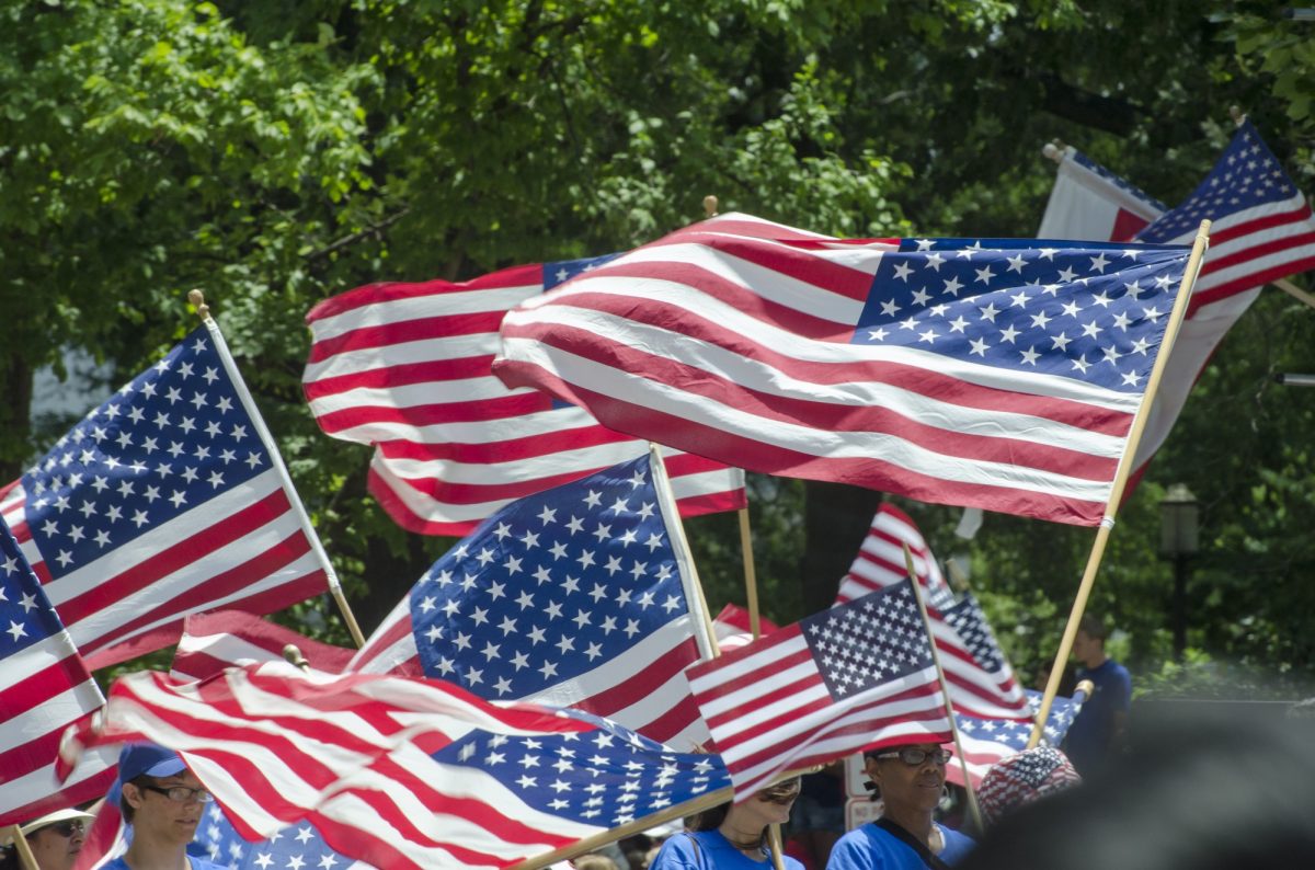 People waving the American flag as they march in Washington D.C on 4th of July in 2014.