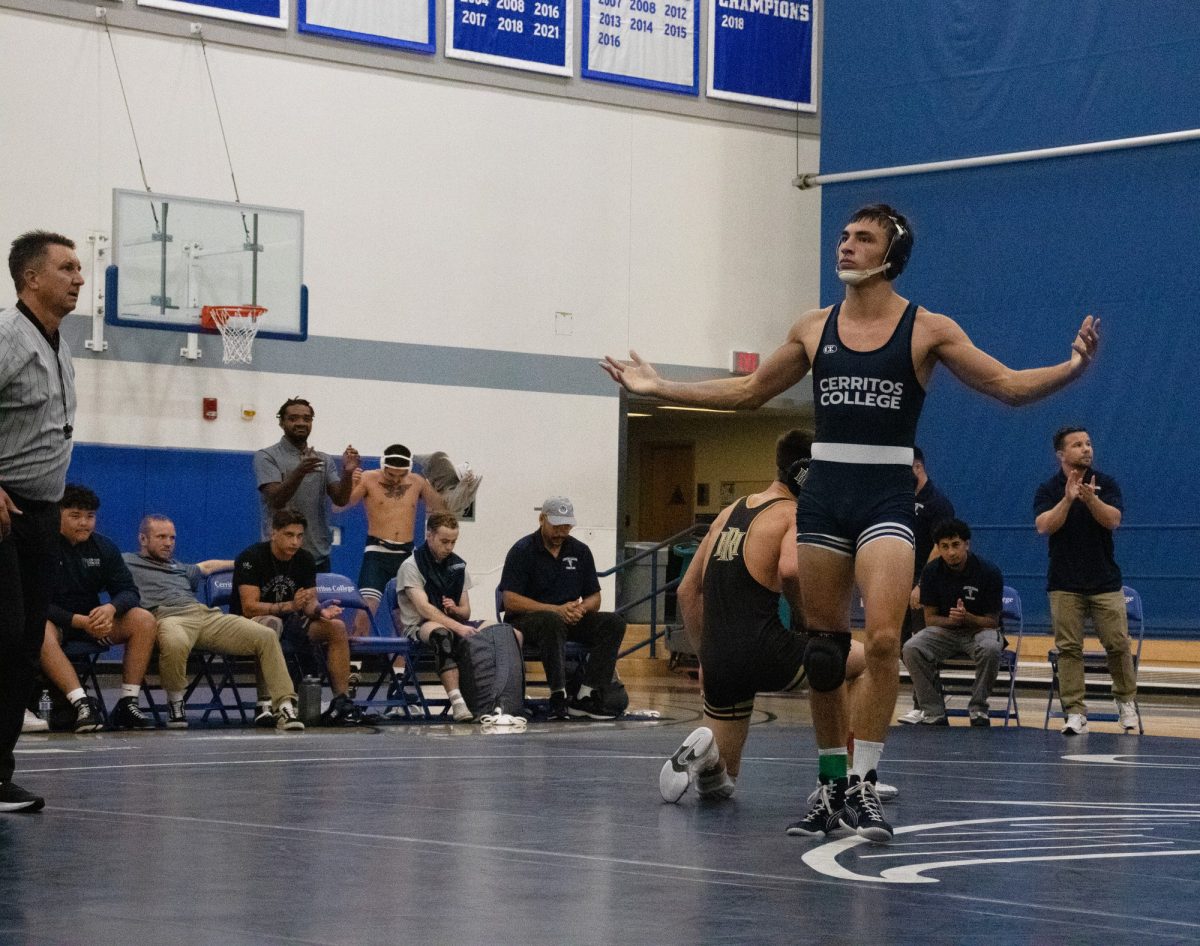 Noah Zuniga wrestling at 157 lbs faces the crowd with arms wide open to celebrate his win over his opponent.