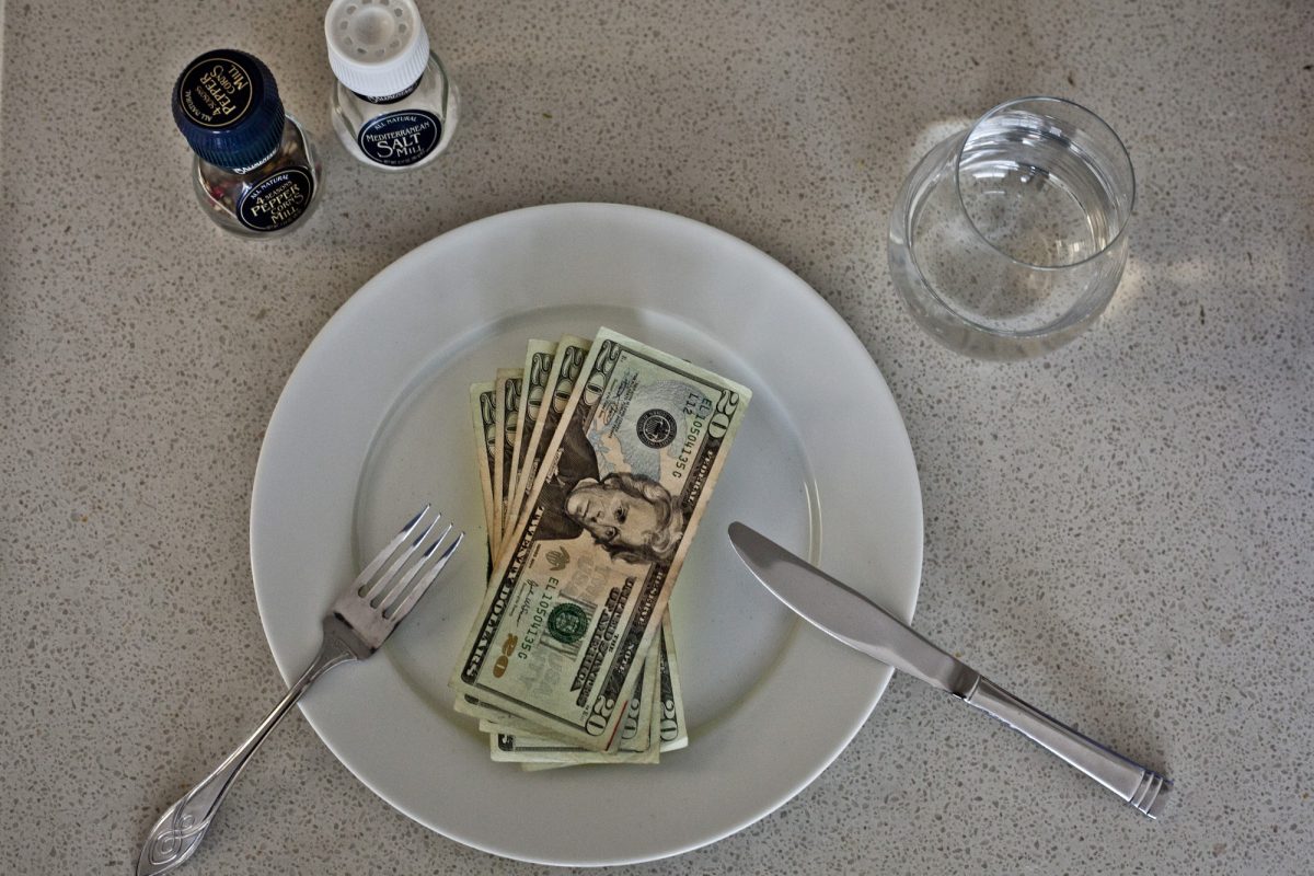 Money being served on a plate next to some silverware. 