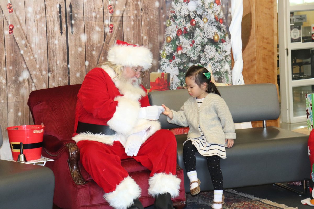 Santa+shaking+a+little+girls+hand+while+they+are+both+seated.+