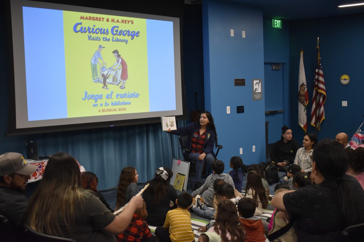 Families reading a Curious George book during bilingual reading time. Photo credit: Dillon Laurer