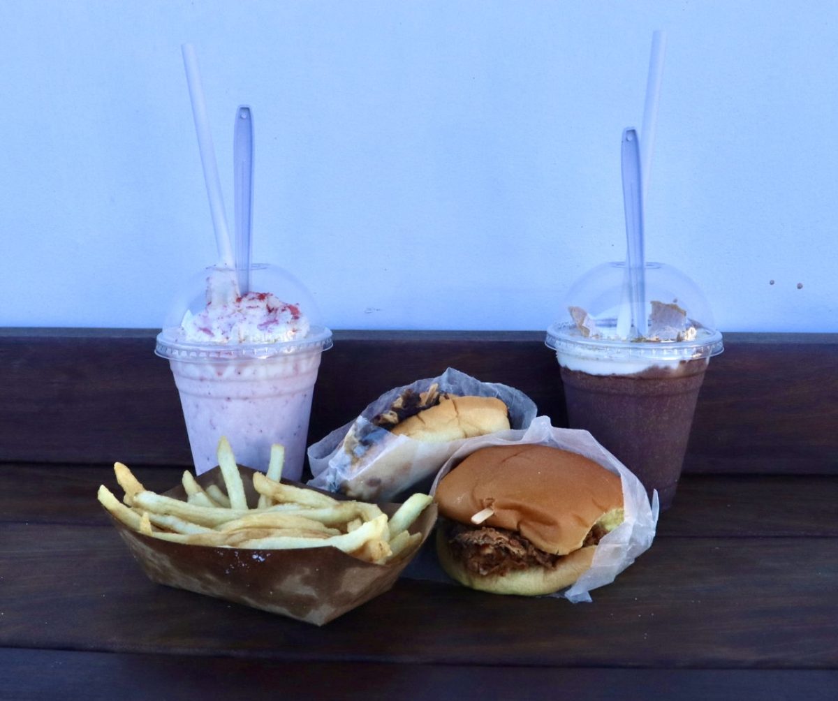 A collection of food from The Win-Dow which includes a strawberry shake, a chocolate shake, a chicken sandwich, a cheeseburger, and a set of fries.