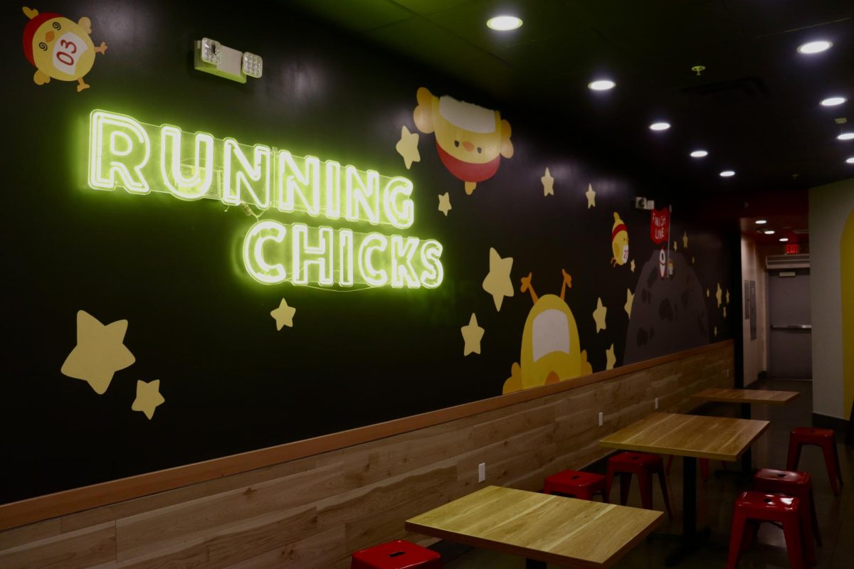 The inside of Running Chicks’ restaurant with an LED sign and seating for customers.