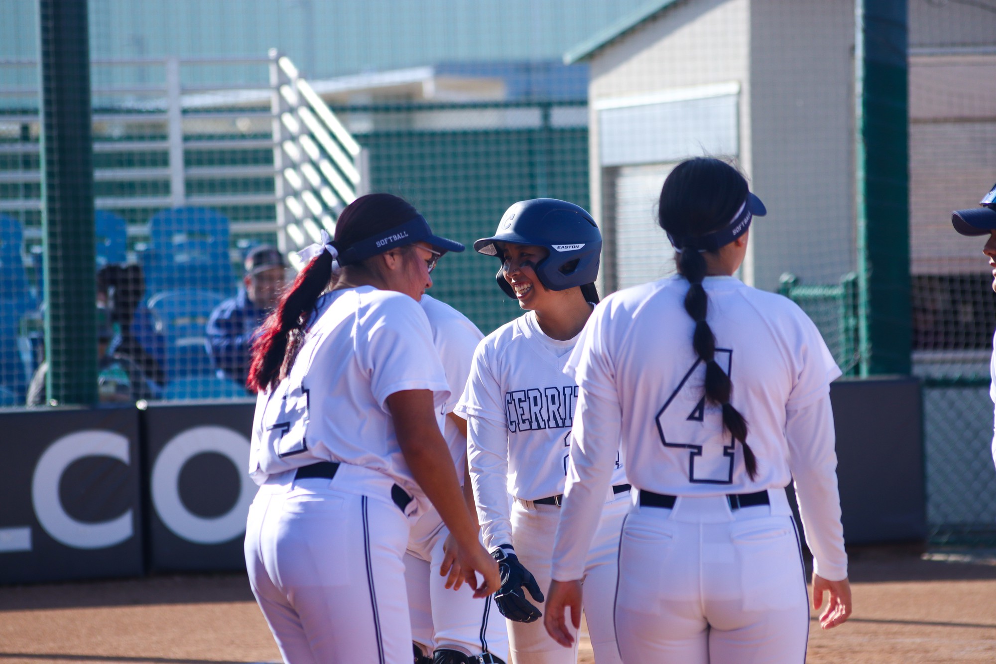 Outfielder, Jocelyn Doan, smiling as she heads back to the dugout giving her teammates high fives.