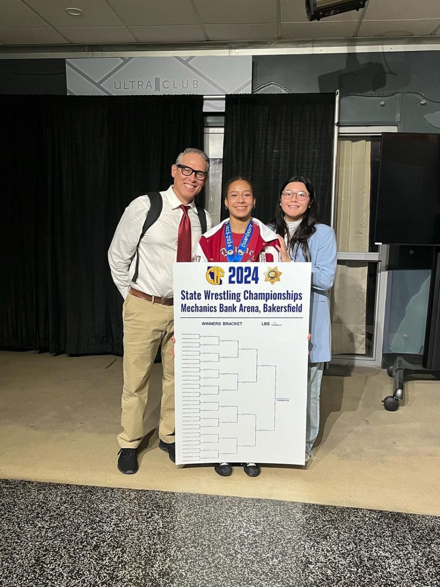 Christina Osorio (middle) proudly holds her State championship bracket with a big smile as she stands between head coach Rios (left) and assistant coach Cuellar (right). Photo credit: Felix Osorio Sr.