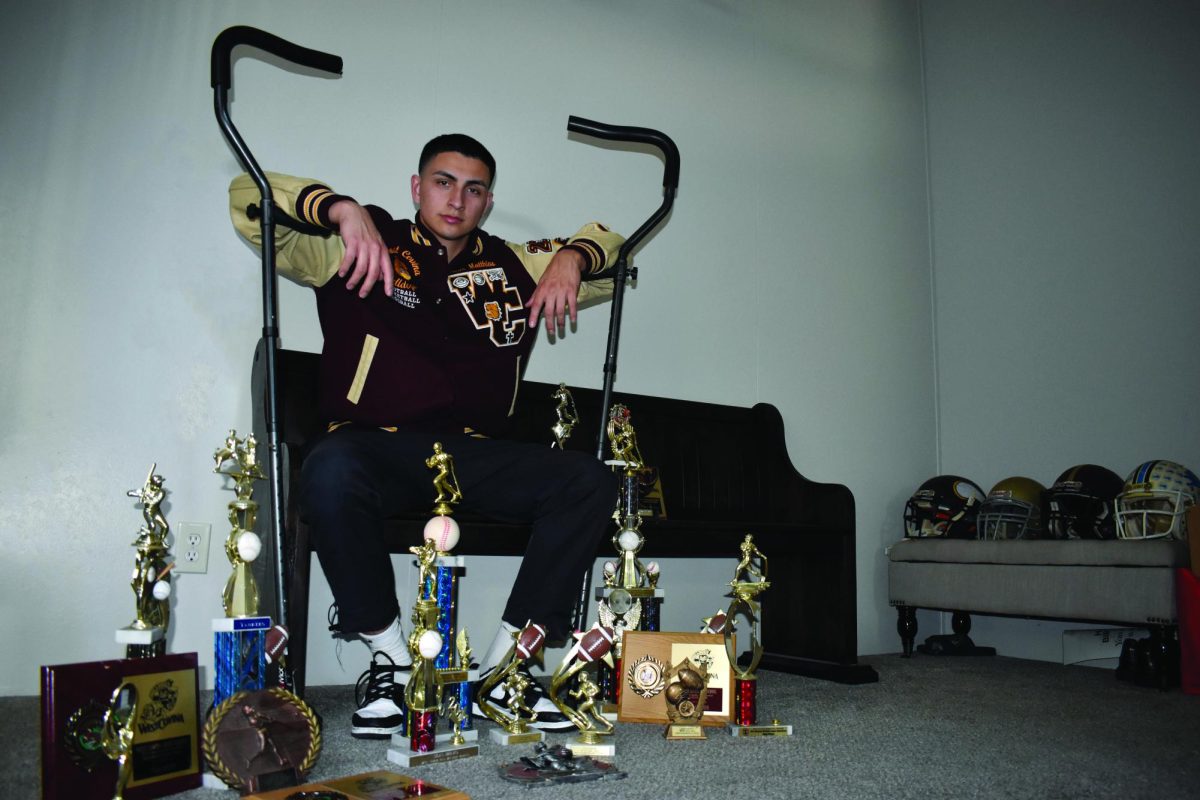 Silas Bravo surrounded by sports and trophies for his college athletic days.
