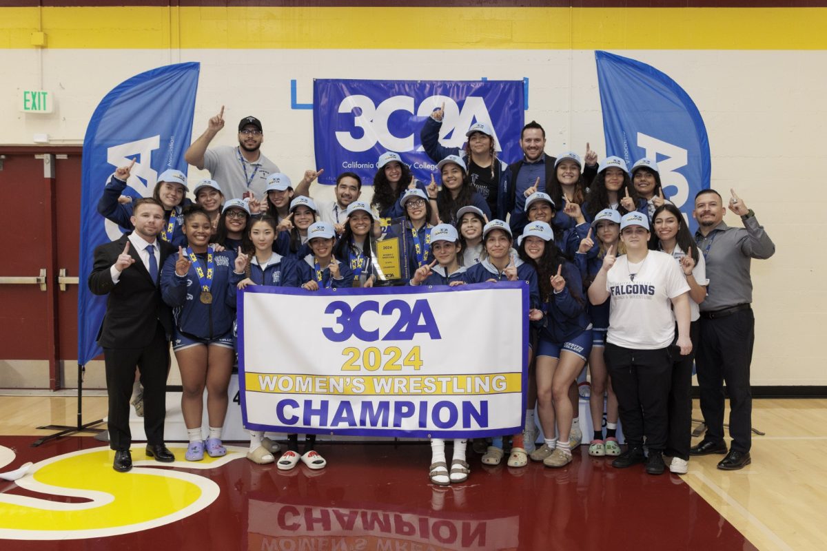 The Cerritos College women’s wrestling team proudly holding up a one and the State Championship banner after claiming the title for the second consecutive season.