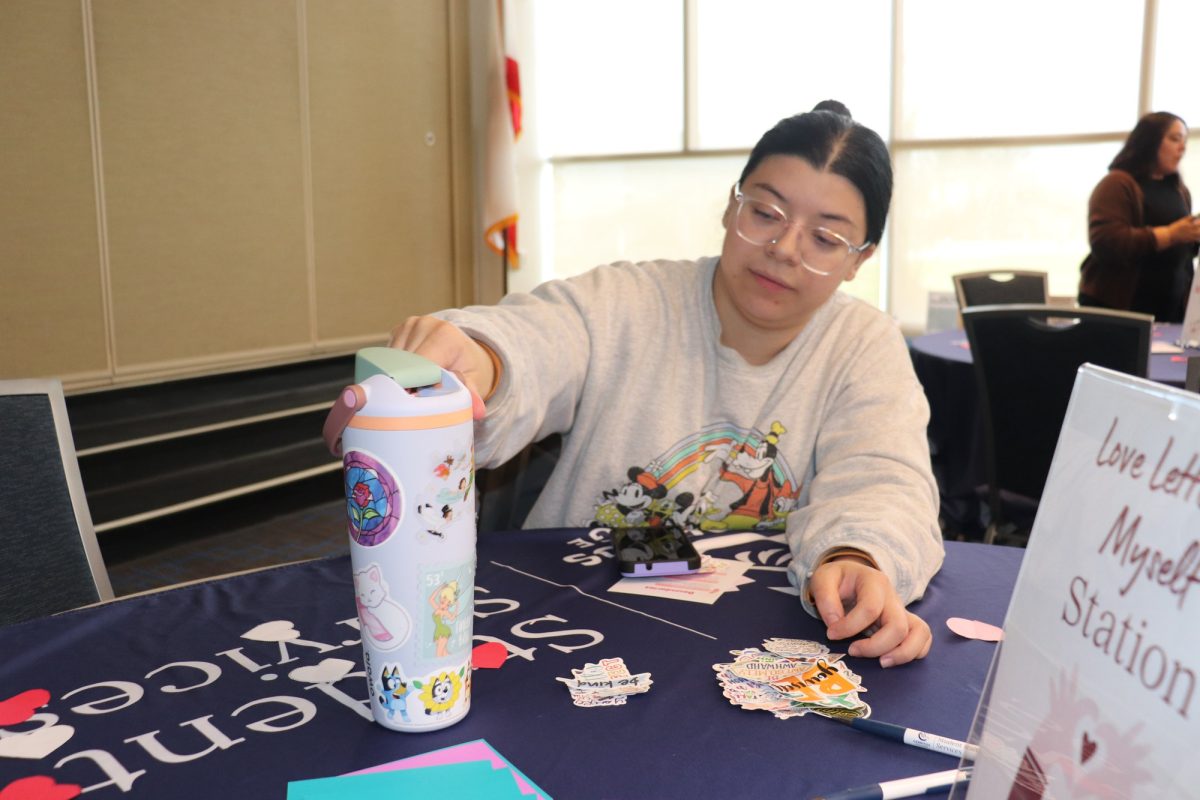 Daisy Unzueta who is majoring in Teaching, hopes to find the final sticker to her flask water bottle from the remaining stickers laid out onto the table. 