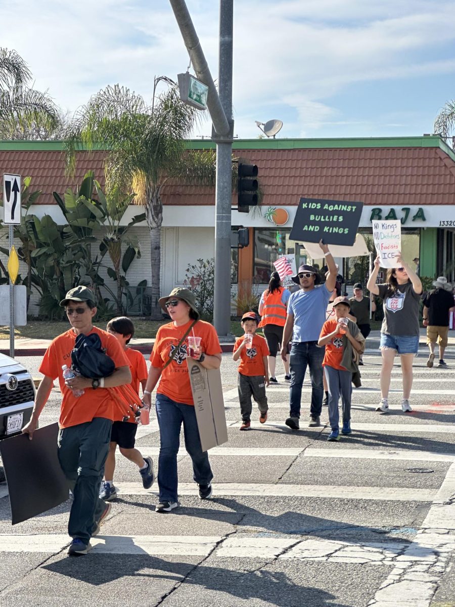 Pictured are Young children and adults with a sign saying “Kids against bullies and kings”. 